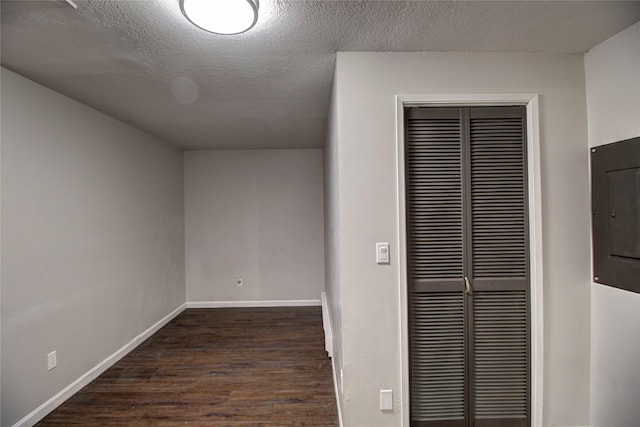 interior space with electric panel, a textured ceiling, baseboards, and dark wood-style flooring