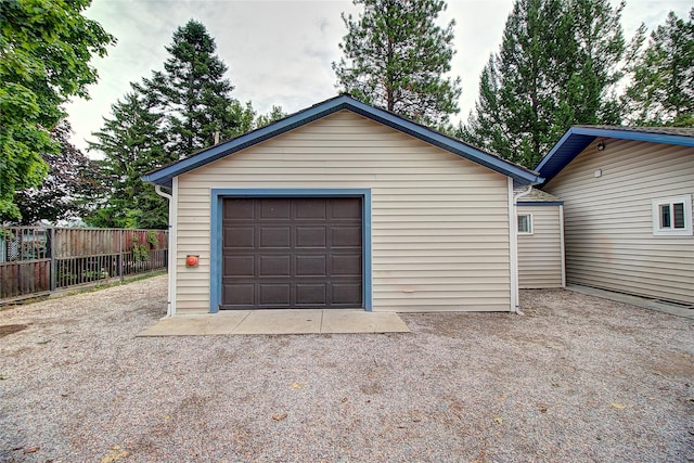 detached garage featuring gravel driveway and fence