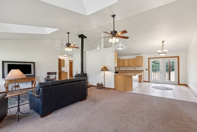 carpeted living room featuring lofted ceiling with skylight, ceiling fan with notable chandelier, and french doors