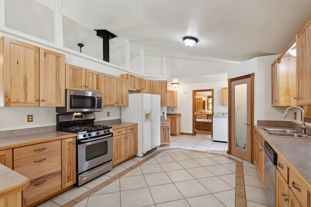 kitchen featuring stainless steel appliances, light brown cabinets, sink, light tile patterned floors, and washer / clothes dryer