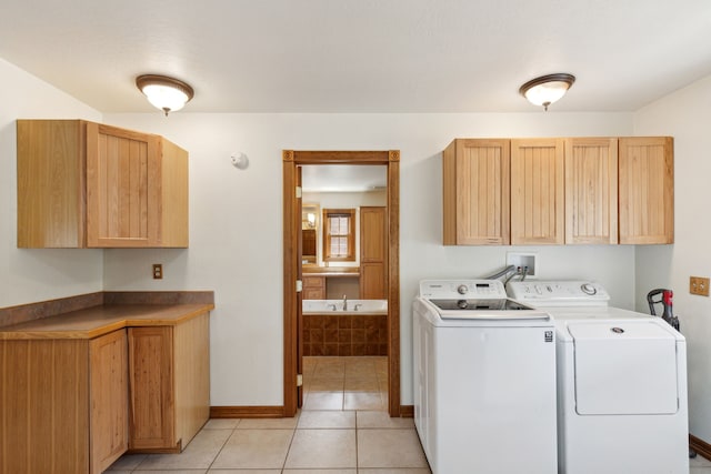 clothes washing area with cabinets, washer and clothes dryer, and light tile patterned floors