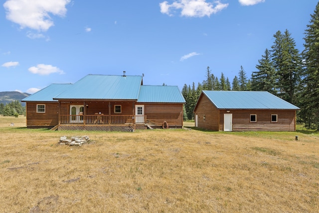 back of house with a deck, an outbuilding, and a lawn