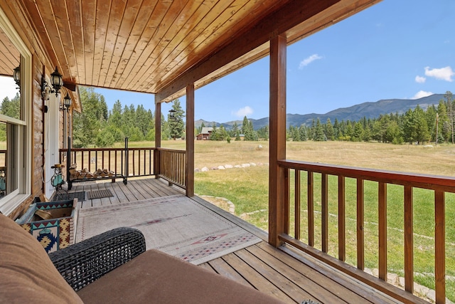 wooden terrace featuring a mountain view and a yard