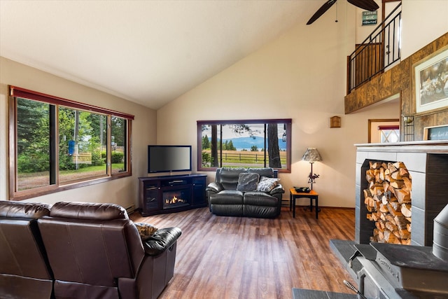 159 Sylvan Dr, Bigfork, MT 59911 - living room featuring a warm lit fireplace, a ceiling fan, high vaulted ceiling, and wood finished floors
