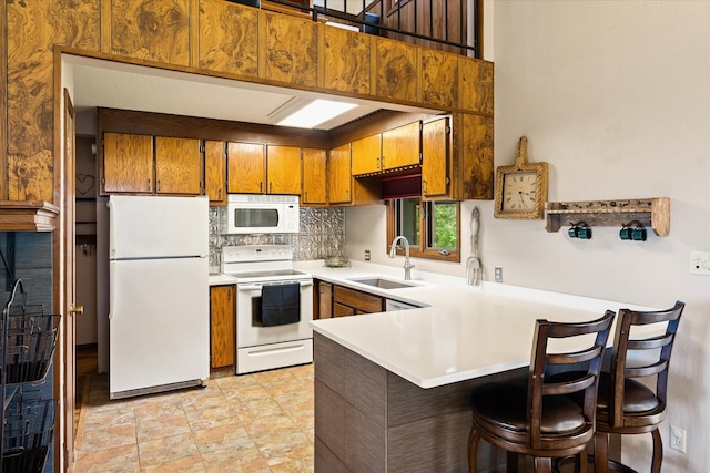 159 Sylvan Dr, Bigfork, MT 59911 - kitchen featuring white appliances, brown cabinets, a peninsula, tasteful backsplash, and light countertops
