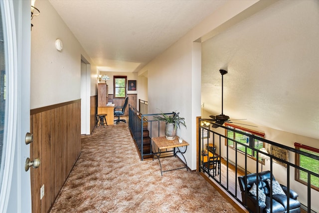 159 Sylvan Dr, Bigfork, MT 59911 - hall with wooden walls, a wainscoted wall, carpet floors, a textured ceiling, and an upstairs landing