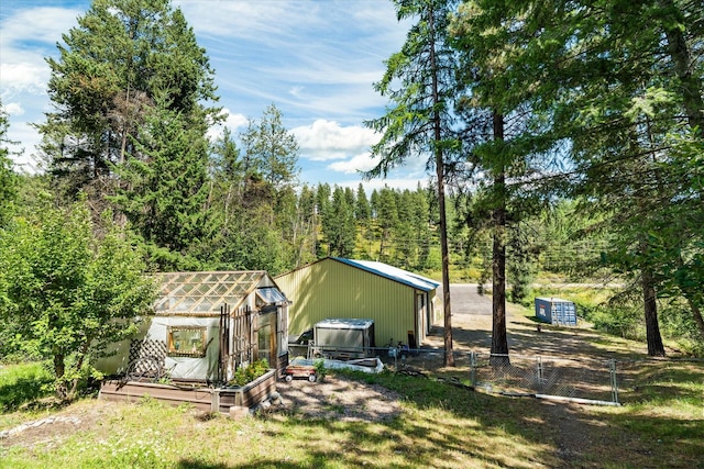 159 Sylvan Dr, Bigfork, MT 59911 - view of front facade with a greenhouse, an outdoor structure, and a view of trees