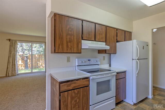 kitchen featuring white appliances and light colored carpet