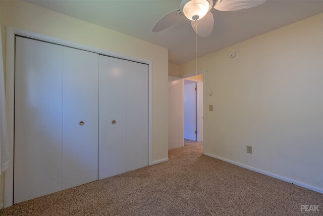 unfurnished bedroom featuring light carpet, a closet, and ceiling fan