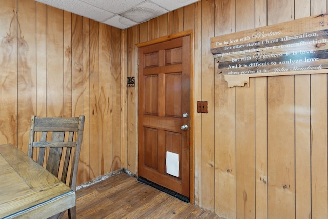 entryway with wooden walls, dark wood finished floors, and a drop ceiling