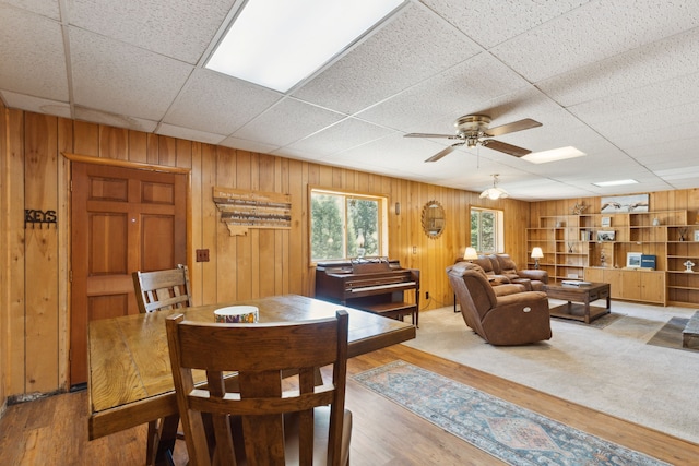 interior space with ceiling fan, wooden walls, and wood finished floors