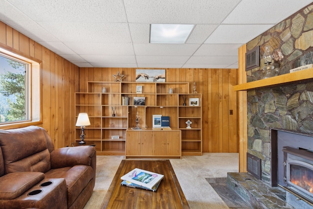 living area with visible vents, light colored carpet, a glass covered fireplace, and wood walls