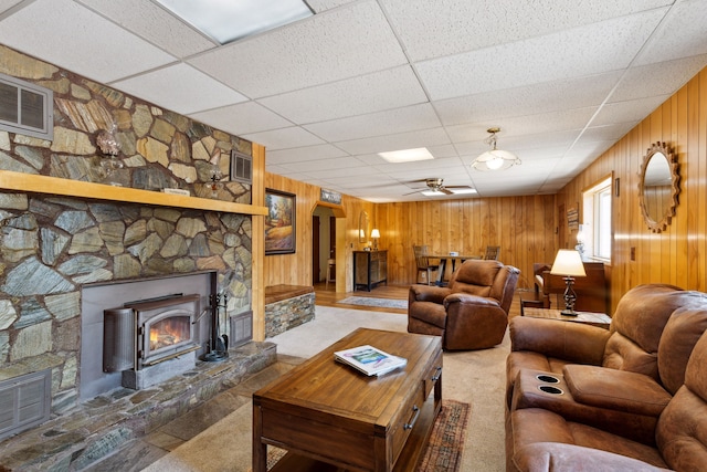 living area featuring a paneled ceiling, visible vents, a fireplace, and wooden walls