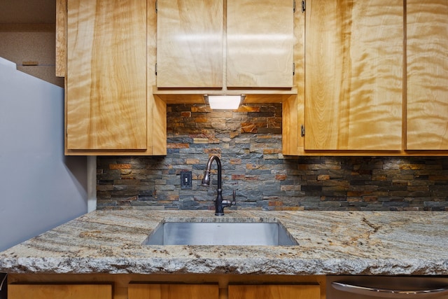 kitchen with a sink, light stone counters, tasteful backsplash, and stainless steel dishwasher