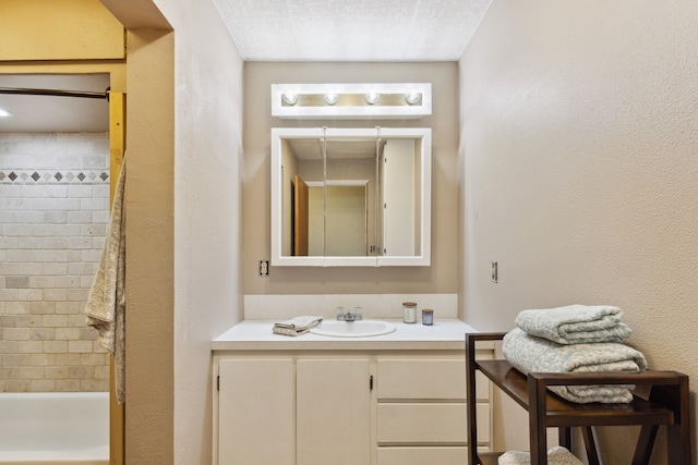 bathroom featuring vanity, bathing tub / shower combination, and a textured wall