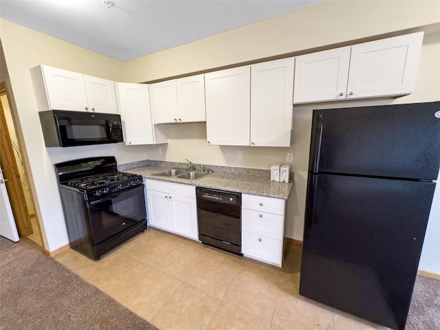 kitchen with sink, light tile patterned floors, white cabinetry, black appliances, and light stone countertops