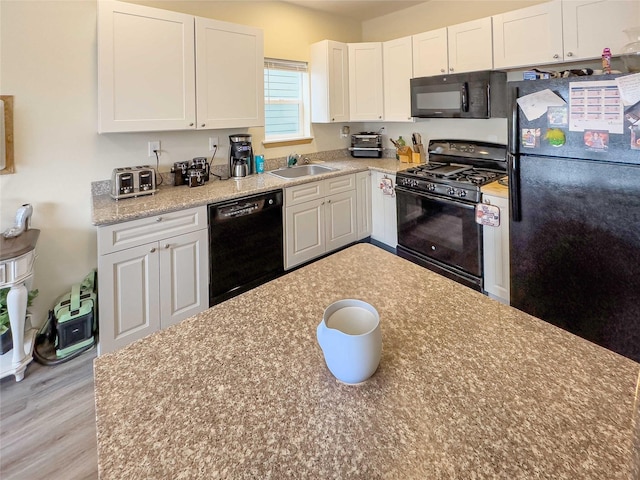 kitchen featuring white cabinetry, light hardwood / wood-style floors, sink, and black appliances