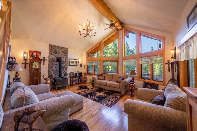 living room featuring high vaulted ceiling, light wood-type flooring, beam ceiling, a wood stove, and ceiling fan with notable chandelier