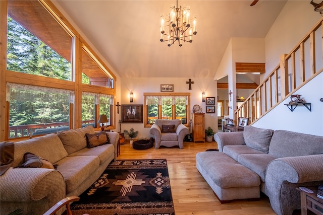 living room featuring a notable chandelier, high vaulted ceiling, and light wood-type flooring