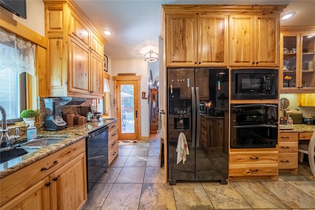 kitchen with sink, light stone counters, light brown cabinetry, light tile patterned floors, and black appliances