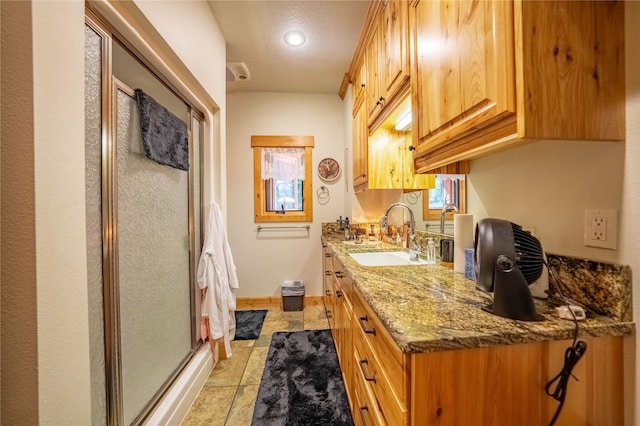 kitchen with sink, light stone counters, and light tile patterned floors