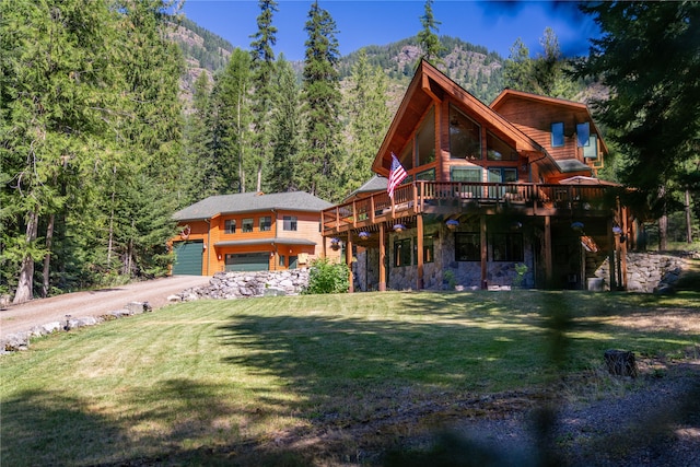 exterior space with a garage, a front lawn, and a deck with mountain view