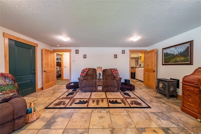 living room featuring light tile patterned floors, a wood stove, and a textured ceiling