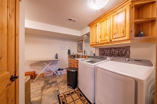 clothes washing area featuring sink, washing machine and clothes dryer, cabinets, a textured ceiling, and light tile patterned flooring