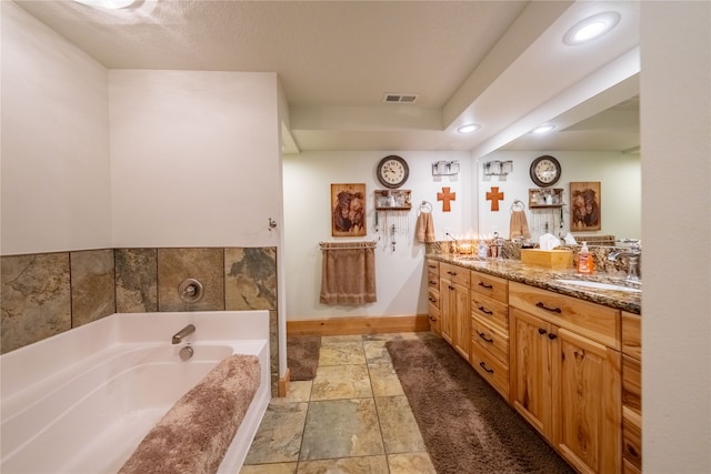 bathroom with a bathtub, double vanity, tile patterned floors, and a textured ceiling