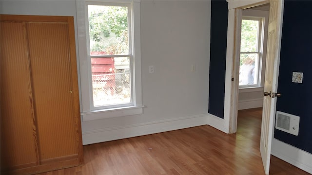 unfurnished bedroom featuring multiple windows and wood-type flooring