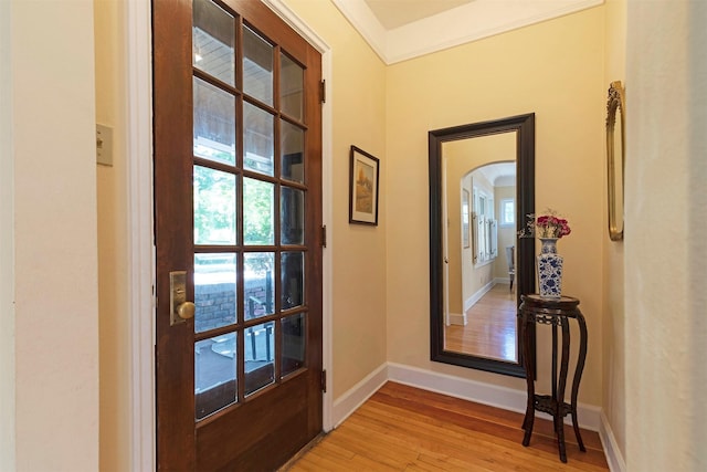 entryway with ornamental molding, a healthy amount of sunlight, and light hardwood / wood-style flooring