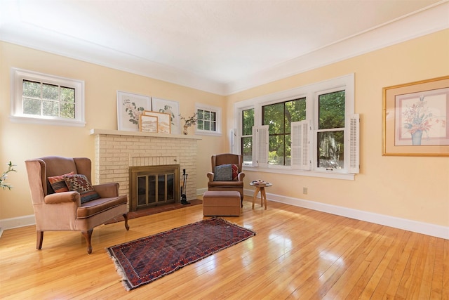 sitting room featuring a brick fireplace, light hardwood / wood-style flooring, and plenty of natural light