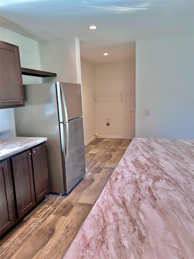 kitchen with dark brown cabinetry, stainless steel refrigerator, and light wood-type flooring