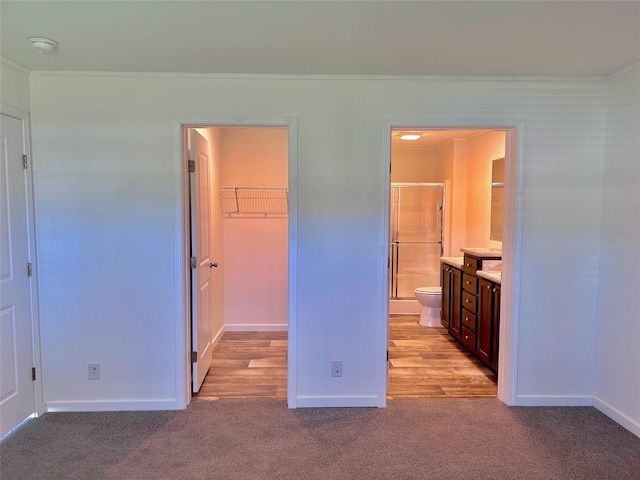 unfurnished bedroom with crown molding, a walk in closet, and light carpet