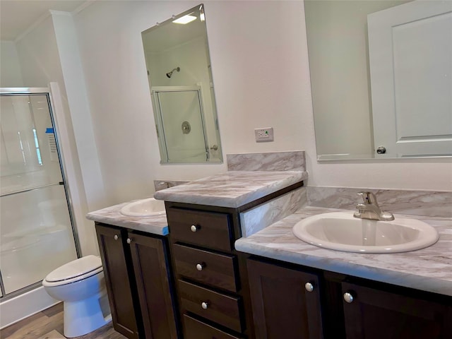 bathroom with a shower with shower door, wood-type flooring, vanity, ornamental molding, and toilet