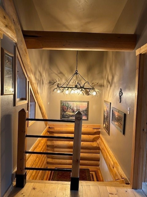 stairs featuring beamed ceiling and hardwood / wood-style flooring