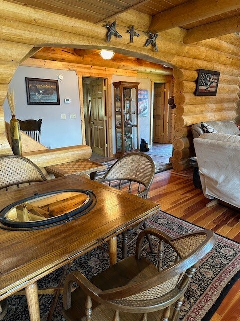 living room featuring hardwood / wood-style floors, beam ceiling, wooden ceiling, and rustic walls