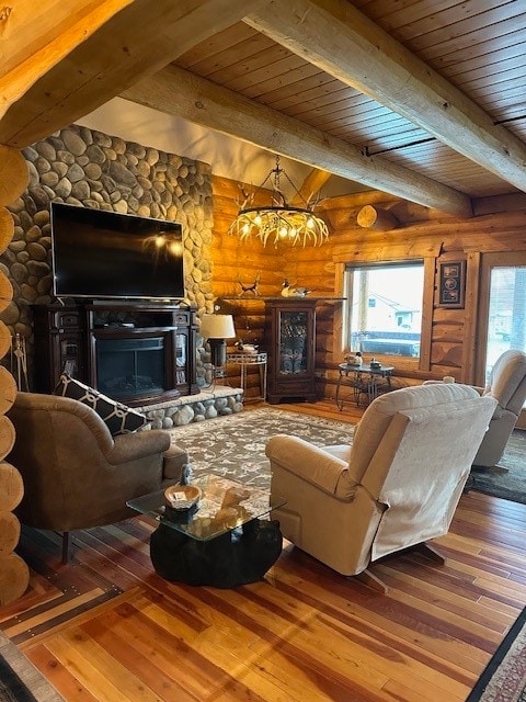 living room with hardwood / wood-style flooring, beamed ceiling, rustic walls, a stone fireplace, and a notable chandelier