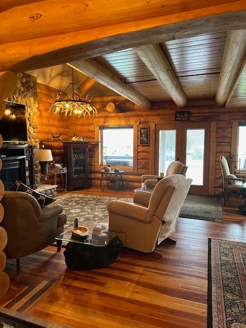 living room with a healthy amount of sunlight, wood-type flooring, a chandelier, and vaulted ceiling with beams