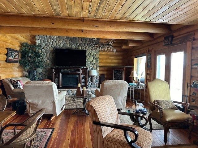 living room with hardwood / wood-style floors, wooden ceiling, beamed ceiling, a stone fireplace, and log walls