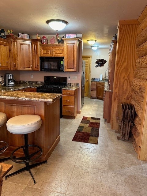 kitchen with light stone counters, black appliances, a breakfast bar, and kitchen peninsula