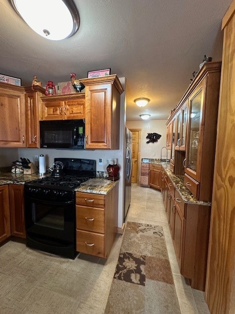 kitchen featuring sink, black appliances, light stone countertops, and a textured ceiling