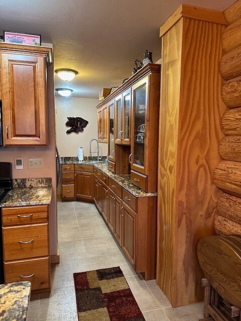 kitchen with a textured ceiling, sink, and dark stone counters