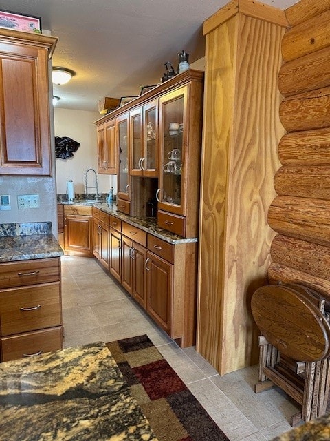 kitchen with dark stone countertops, sink, and rustic walls