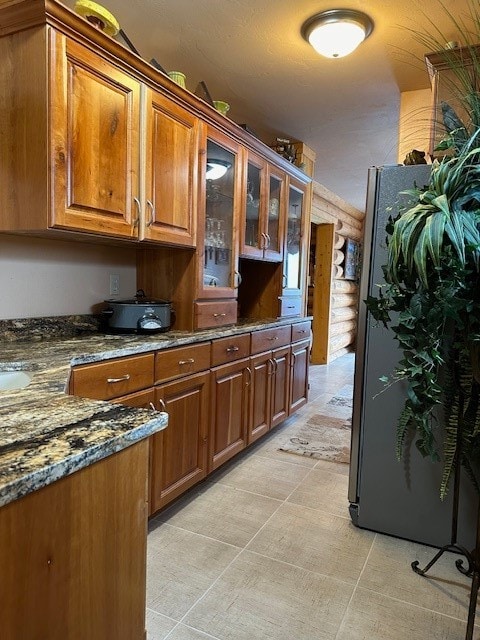 kitchen featuring dark stone counters and stainless steel refrigerator