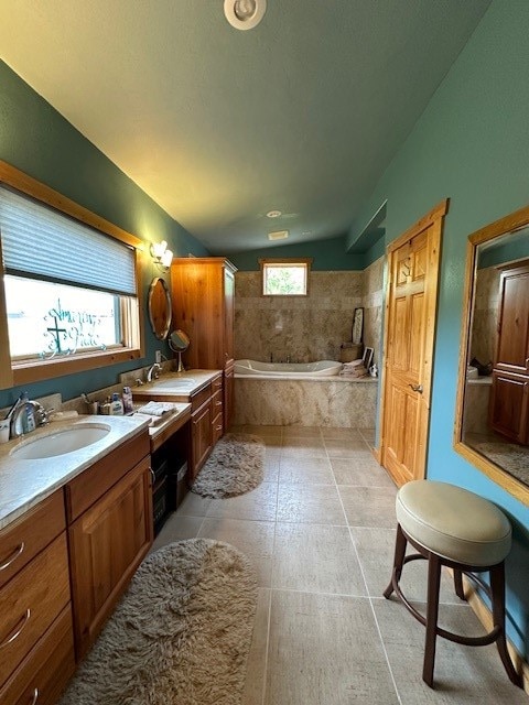 bathroom featuring vanity, lofted ceiling, a wealth of natural light, and tiled tub