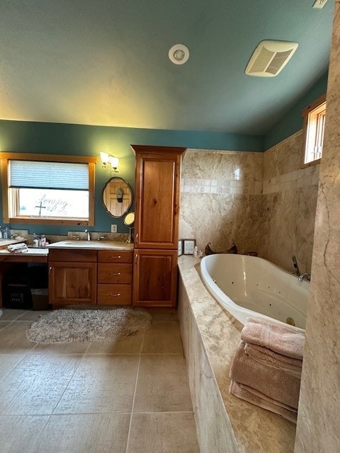 bathroom with tile walls, vanity, a relaxing tiled tub, and tile patterned flooring