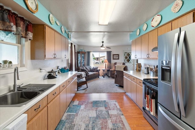 kitchen featuring sink, a textured ceiling, stainless steel appliances, light hardwood / wood-style floors, and backsplash