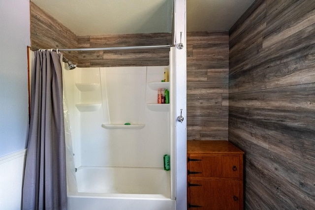 full bathroom featuring shower / bath combo with shower curtain and wooden walls