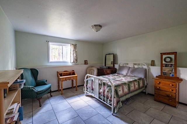 tiled bedroom featuring a wainscoted wall